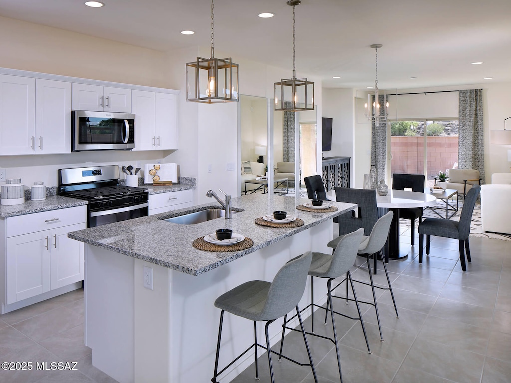kitchen with white cabinets, a sink, stainless steel appliances, and light stone countertops