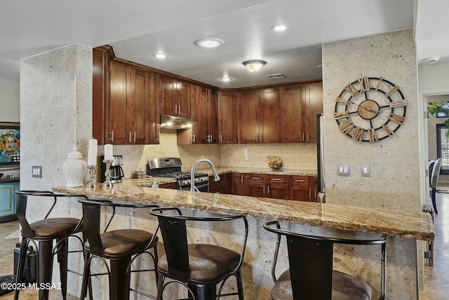 3167 N Corona Pl, Nogales, AZ 85621 - kitchen with light stone counters, gas range, under cabinet range hood, and decorative backsplash