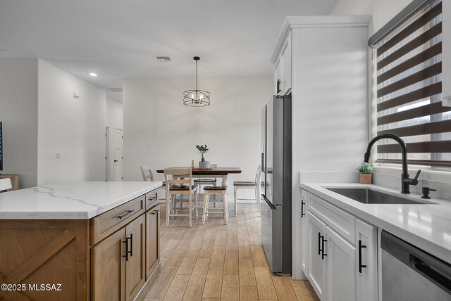 kitchen with decorative light fixtures, light wood-type flooring, a sink, visible vents, and appliances with stainless steel finishes