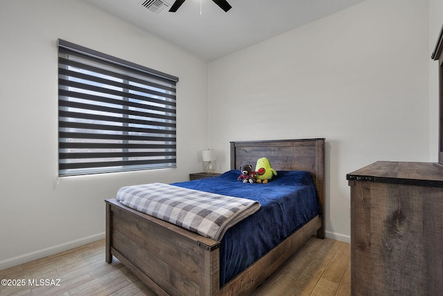 bedroom featuring baseboards, visible vents, wood finished floors, and a ceiling fan