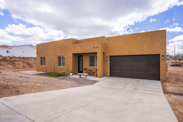 adobe home with stucco siding, driveway, and a garage