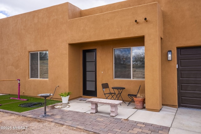 entrance to property with stucco siding and a patio