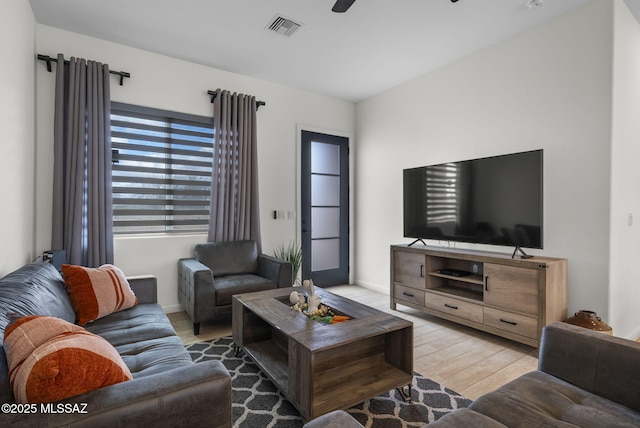 living area featuring wood finished floors, baseboards, and visible vents