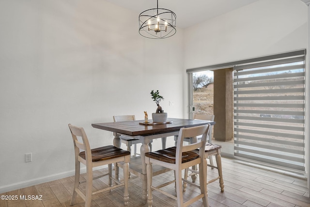 dining area featuring an inviting chandelier, baseboards, and light wood-type flooring