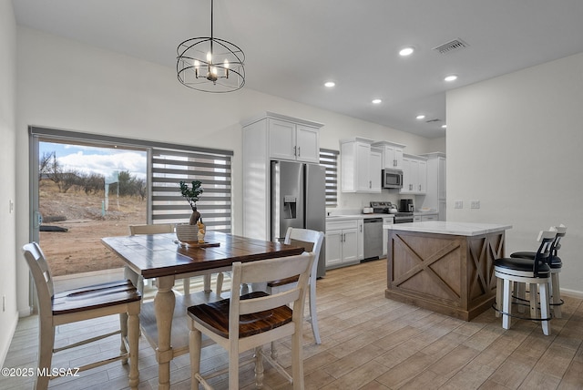 dining area featuring light wood-style flooring, baseboards, visible vents, recessed lighting, and an inviting chandelier