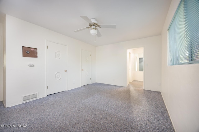 carpeted empty room featuring visible vents and ceiling fan