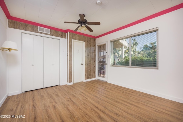 unfurnished bedroom with a closet, visible vents, crown molding, baseboards, and wood finished floors