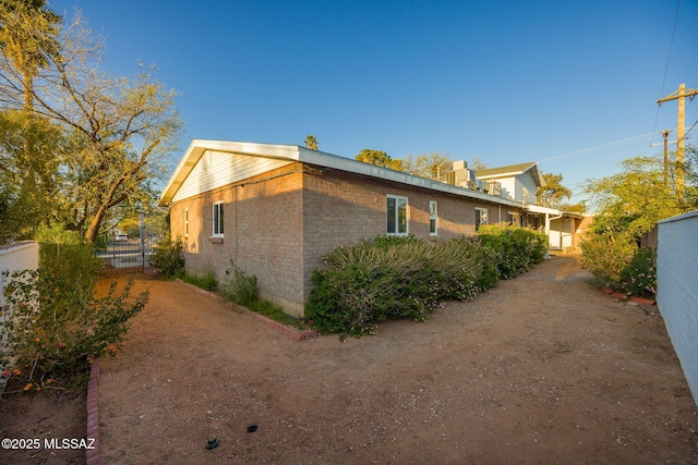view of side of property featuring brick siding and fence