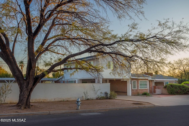 traditional-style house featuring driveway and a fenced front yard