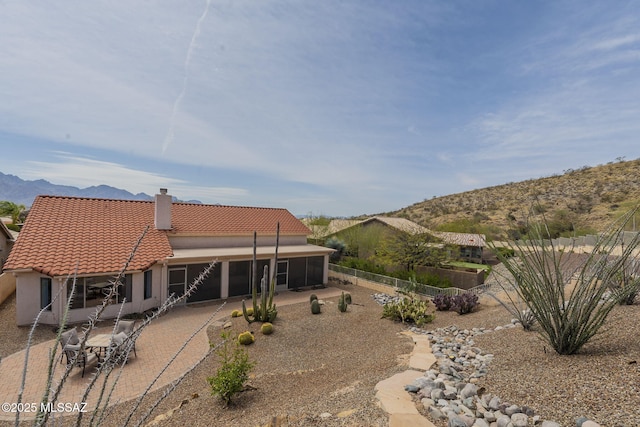 back of property with a mountain view, a tiled roof, fence, a patio, and stucco siding