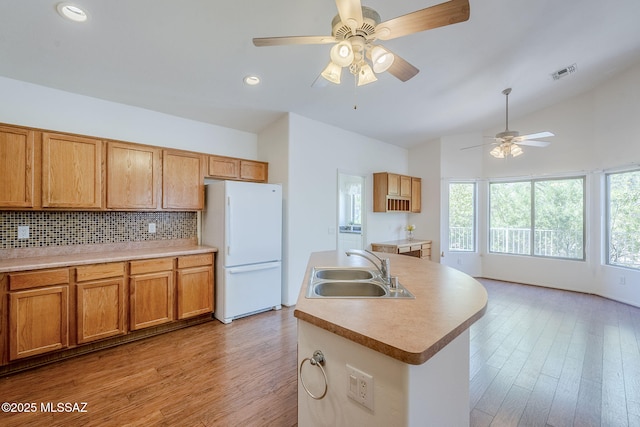 kitchen featuring a sink, ceiling fan, backsplash, visible vents, and freestanding refrigerator