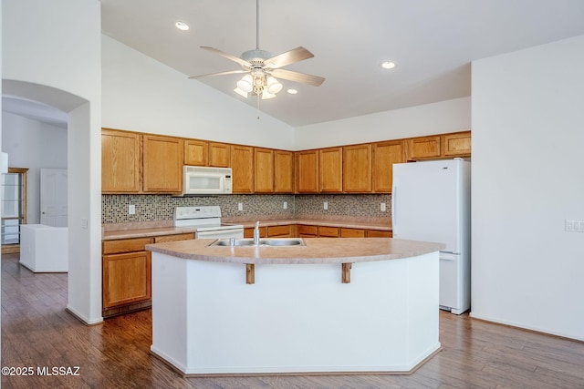 kitchen with a sink, white appliances, ceiling fan, light countertops, and backsplash
