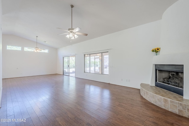 unfurnished living room featuring wood finished floors, high vaulted ceiling, a fireplace with raised hearth, and ceiling fan