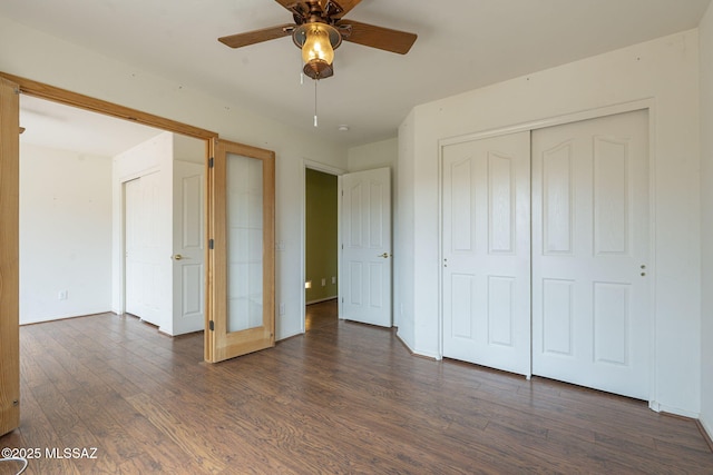 unfurnished bedroom with ceiling fan, a closet, baseboards, and dark wood-style flooring