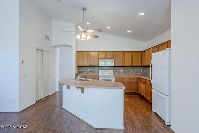 kitchen featuring a ceiling fan, decorative backsplash, white appliances, light countertops, and dark wood finished floors