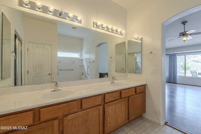 bathroom featuring a sink, ceiling fan, double vanity, and baseboards