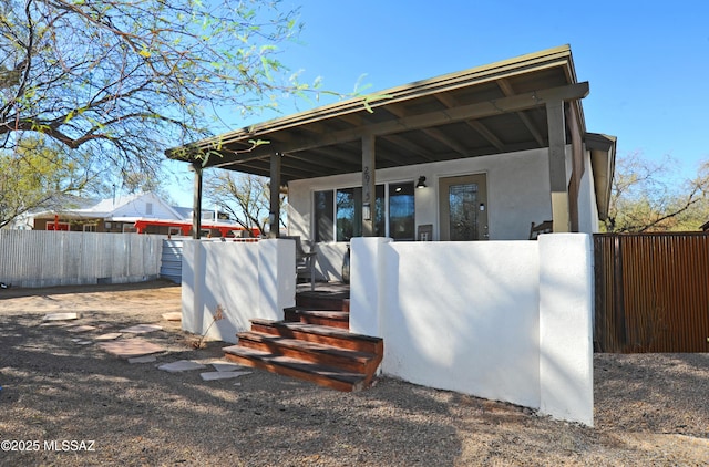 view of outdoor structure with covered porch and fence