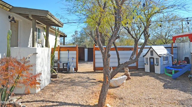 view of yard with fence, a storage unit, and an outdoor structure