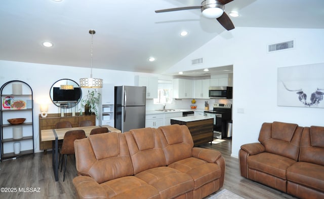 living area featuring a ceiling fan, wood finished floors, lofted ceiling, and visible vents
