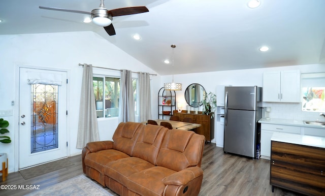 living area featuring a ceiling fan, light wood-style flooring, vaulted ceiling, and recessed lighting