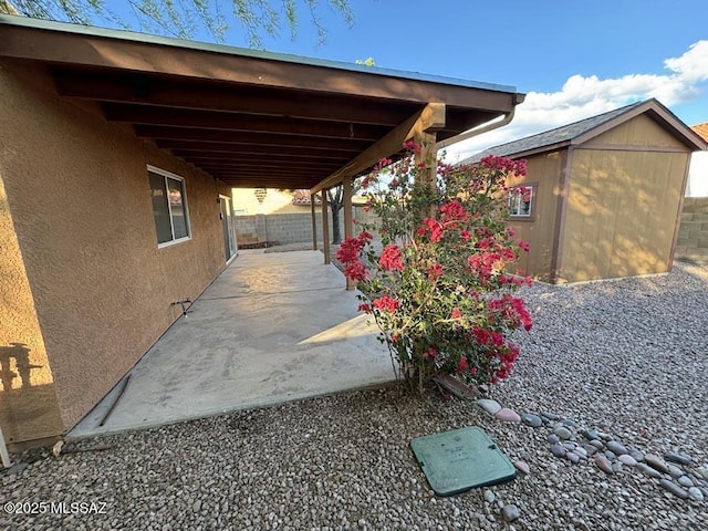 view of patio / terrace with an outbuilding, a fenced backyard, and a shed
