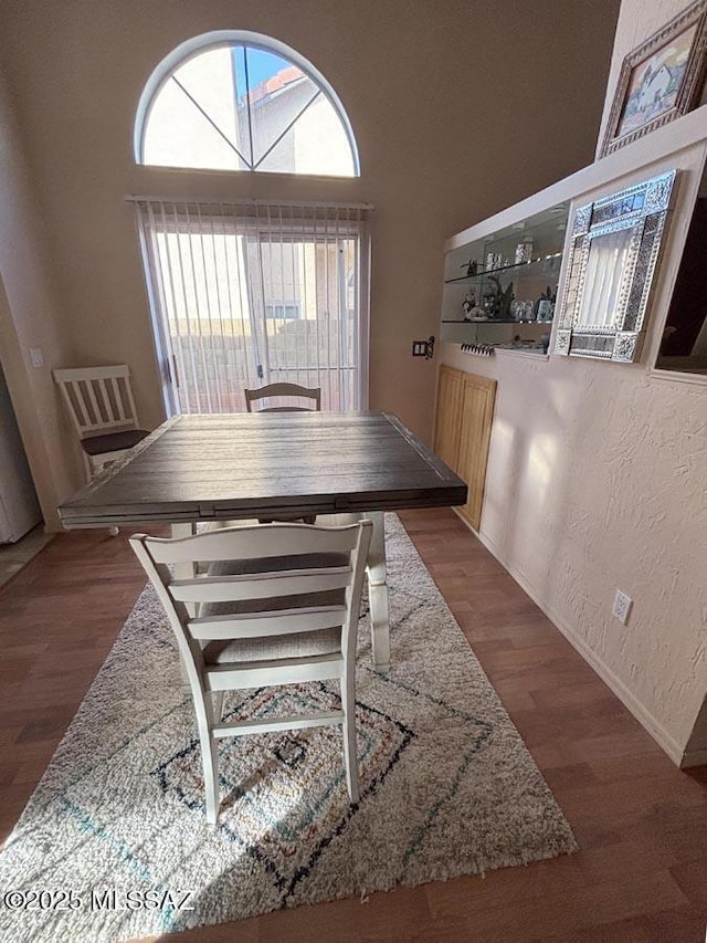 dining space featuring baseboards, a textured wall, and wood finished floors