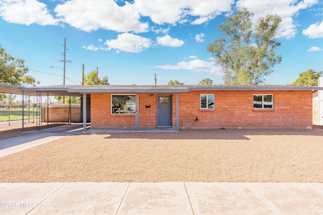 ranch-style home featuring brick siding, fence, concrete driveway, and a carport
