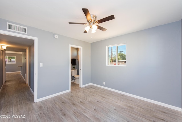 unfurnished bedroom with baseboards, ensuite bath, light wood finished floors, ceiling fan, and visible vents