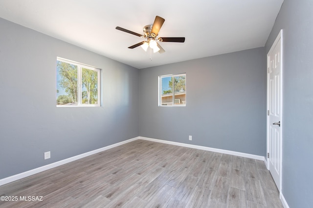 spare room featuring plenty of natural light, baseboards, light wood finished floors, and a ceiling fan