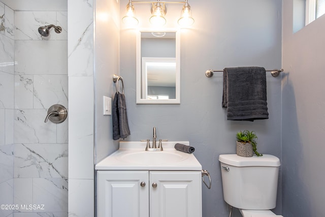 bathroom featuring toilet, vanity, and tiled shower
