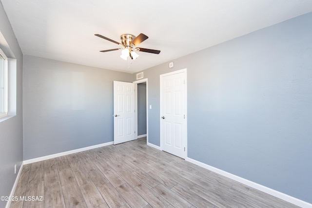 empty room with a ceiling fan, baseboards, light wood-style flooring, and visible vents