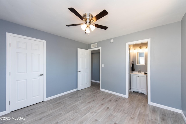 unfurnished bedroom featuring light wood finished floors, baseboards, visible vents, and ensuite bathroom