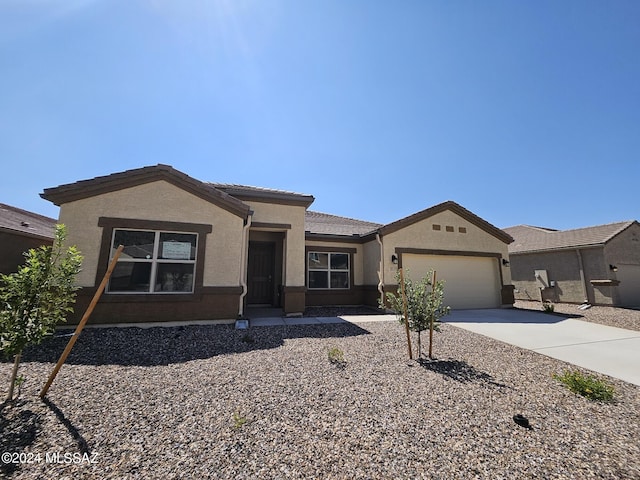 view of front of home with a tile roof, driveway, stucco siding, and an attached garage