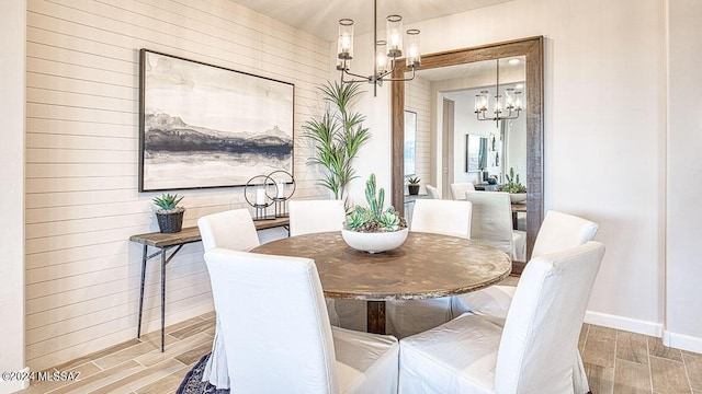 dining room featuring wood tiled floor, baseboards, and an inviting chandelier