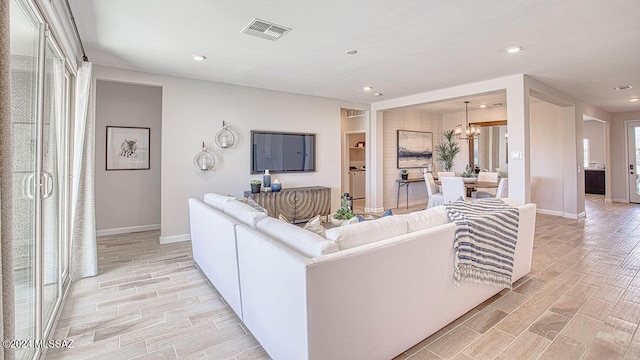 living area featuring wood tiled floor, visible vents, recessed lighting, and an inviting chandelier