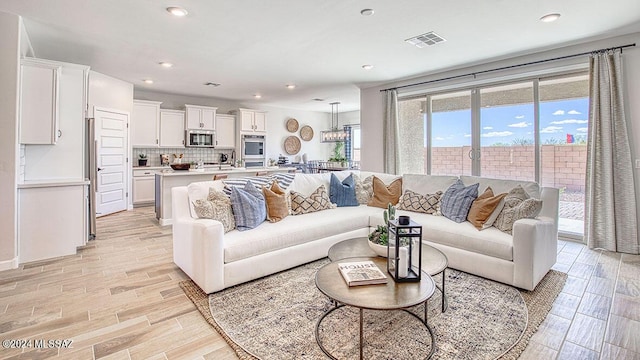 living area featuring visible vents, light wood-style flooring, and recessed lighting
