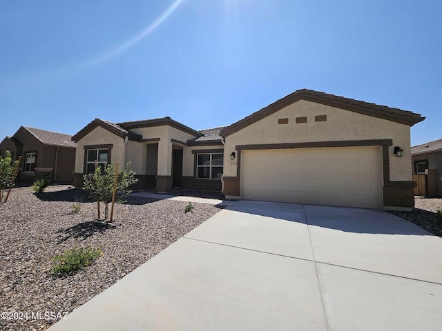 view of front of house with driveway, stucco siding, a tile roof, and a garage