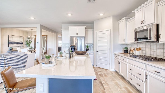 kitchen with white cabinetry, light stone countertops, wood finish floors, stainless steel appliances, and decorative backsplash
