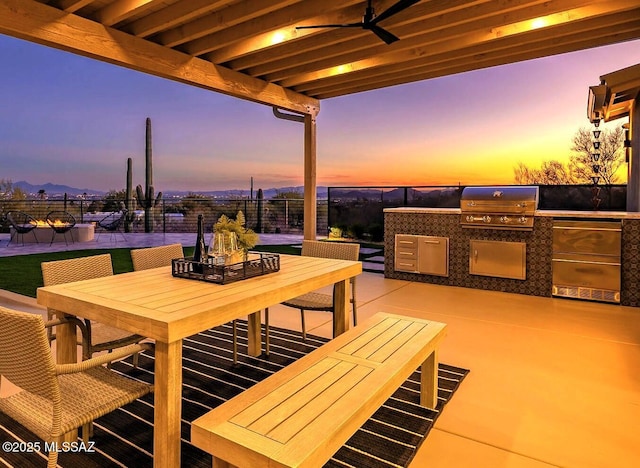 6800 N Cocopas Rd, Tucson, AZ 85718 - patio terrace at dusk with area for grilling, outdoor dining area, fence, and ceiling fan