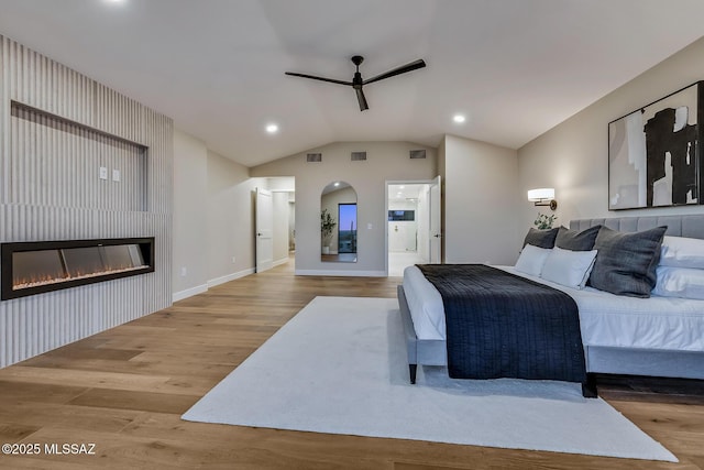 6800 N Cocopas Rd, Tucson, AZ 85718 - bedroom with wood finished floors, a glass covered fireplace, connected bathroom, lofted ceiling, and baseboards