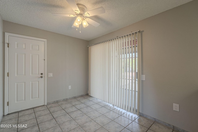 empty room featuring light tile patterned flooring, a textured ceiling, ceiling fan, and baseboards
