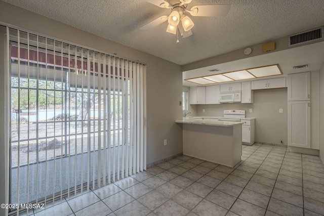 kitchen with visible vents, a peninsula, white appliances, a ceiling fan, and white cabinetry