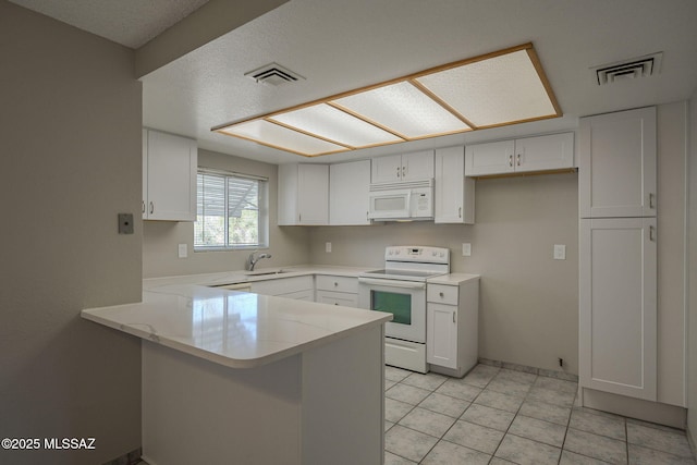 kitchen with visible vents, a peninsula, white appliances, white cabinetry, and a sink