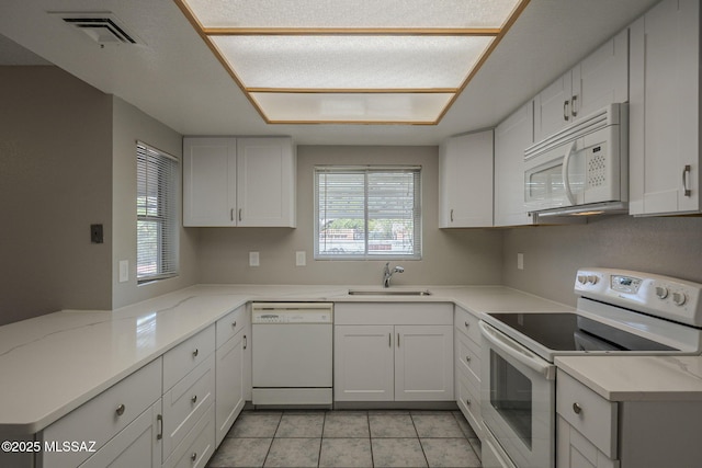 kitchen featuring white cabinetry, white appliances, a sink, visible vents, and a peninsula