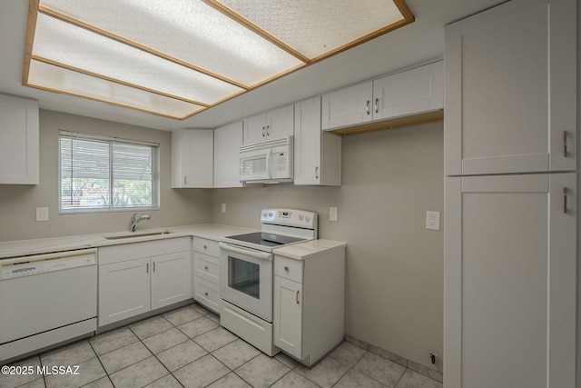 kitchen featuring white appliances, white cabinetry, light countertops, and a sink