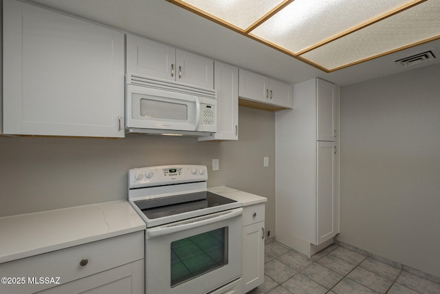 kitchen with white cabinetry, white appliances, light tile patterned floors, visible vents, and light stone countertops