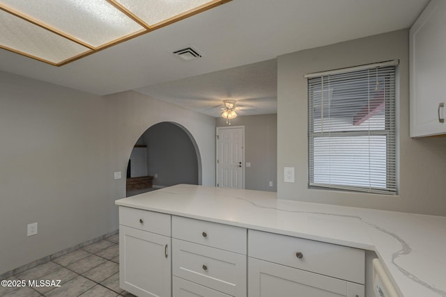 kitchen featuring white cabinets, visible vents, ceiling fan, and light tile patterned floors