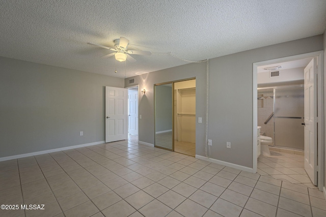 unfurnished bedroom featuring a closet, a textured ceiling, light tile patterned floors, baseboards, and visible vents