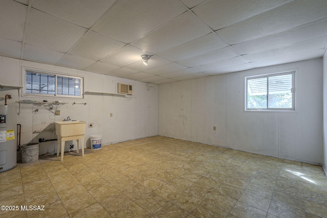 below grade area featuring water heater, a sink, and a paneled ceiling