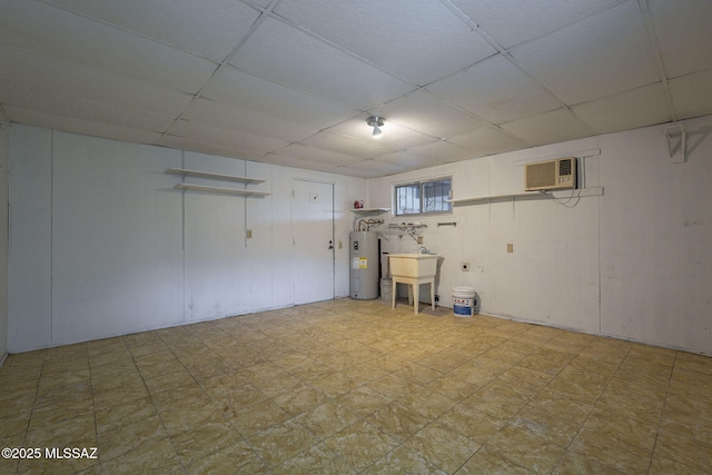 interior space with a drop ceiling, water heater, a sink, and light floors